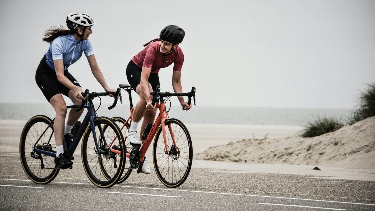 Two cyclists riding road bikes near the shore