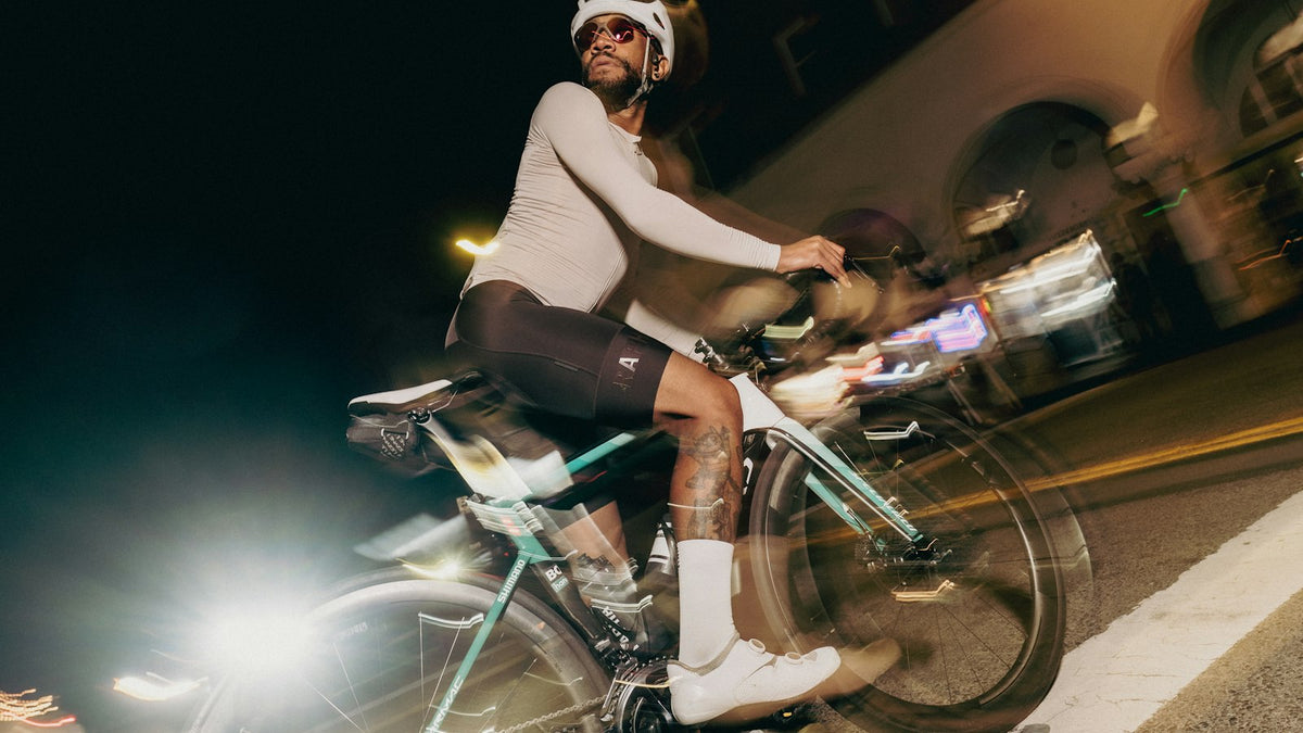 Cyclist riding at night past a lit sign